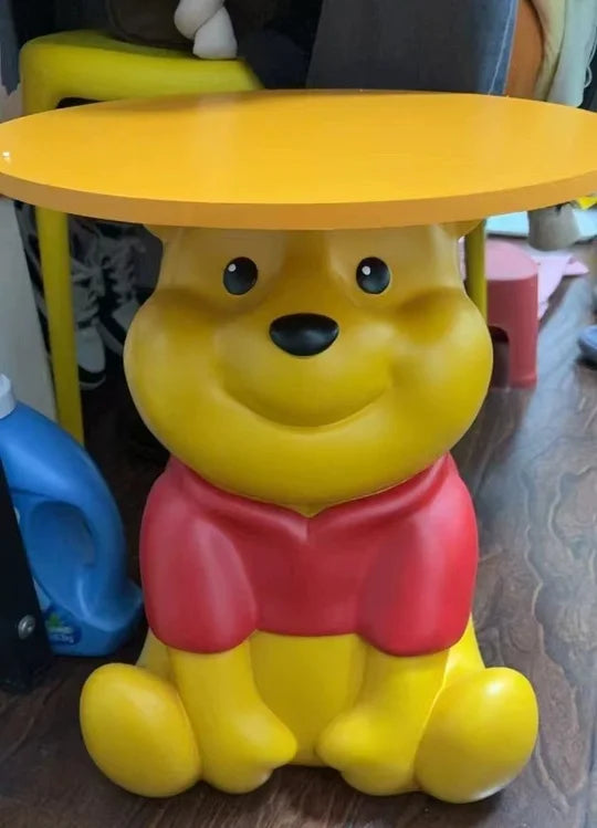 Whinnie the Pooh kidsYellow bear-shaped table with a red shirt on a wooden floor.