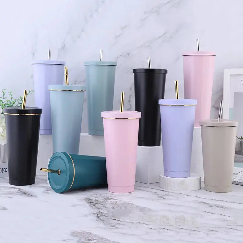 Collection of colorful tumblers with gold straws on a marble surface.