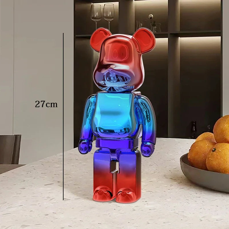 Gradient red to blue bear-shaped figurine on a table with a bowl of oranges in the background. be@rbrick collectable