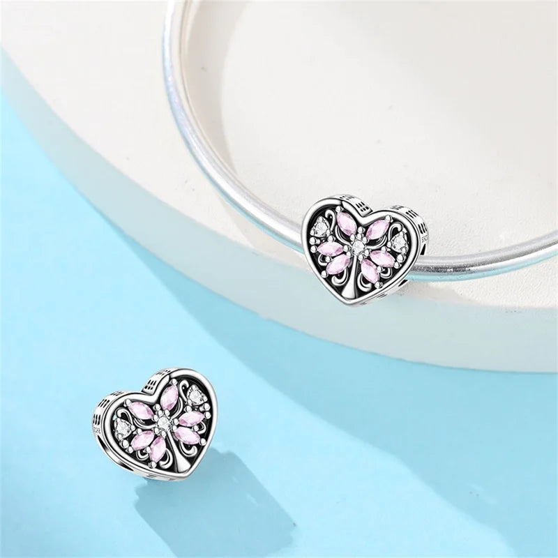 Heart-shaped silver charms with pink accents on a light blue background. pandora style