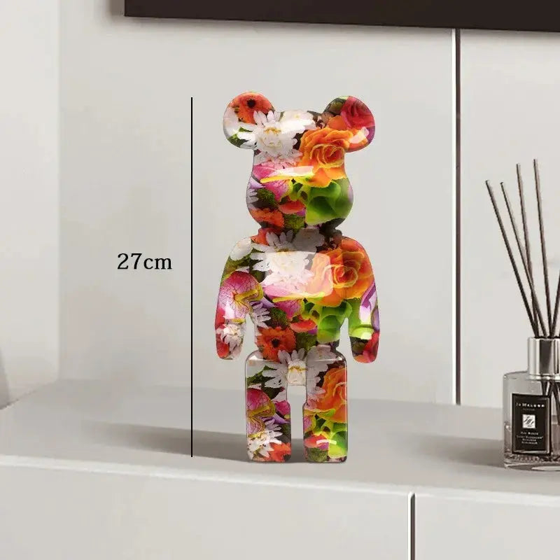 Colorful floral-patterned bear figure on a white surface with a measurement label, next to a diffuser. be@rbrick collectable