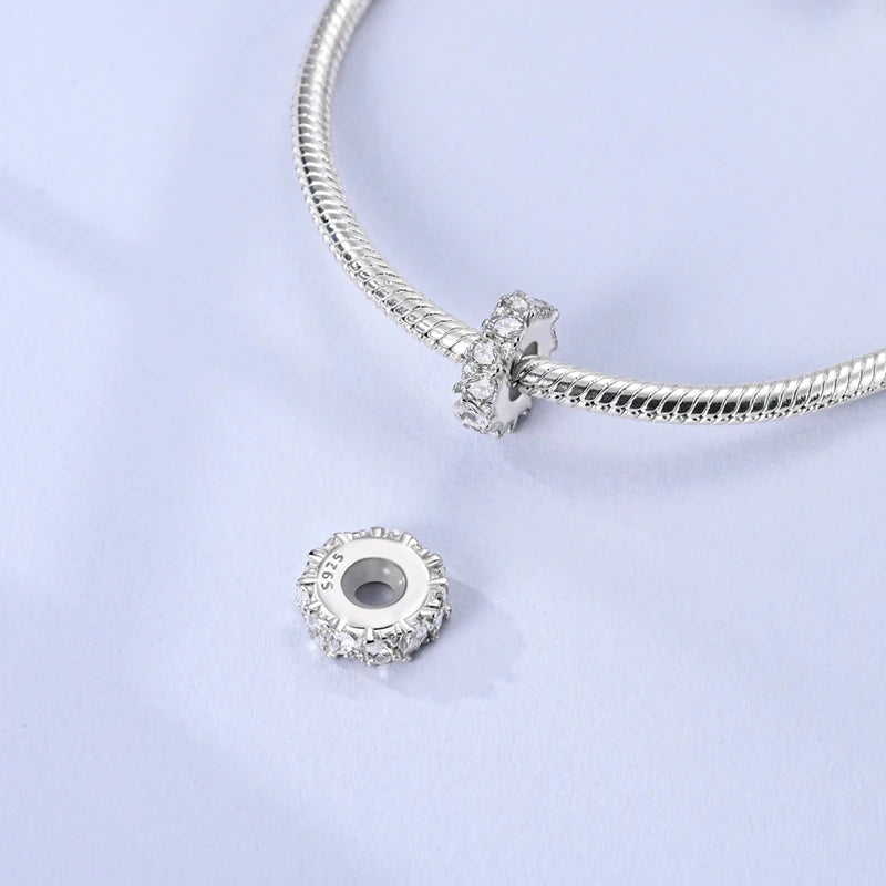 Silver charm with clear gemstone on a light purple background