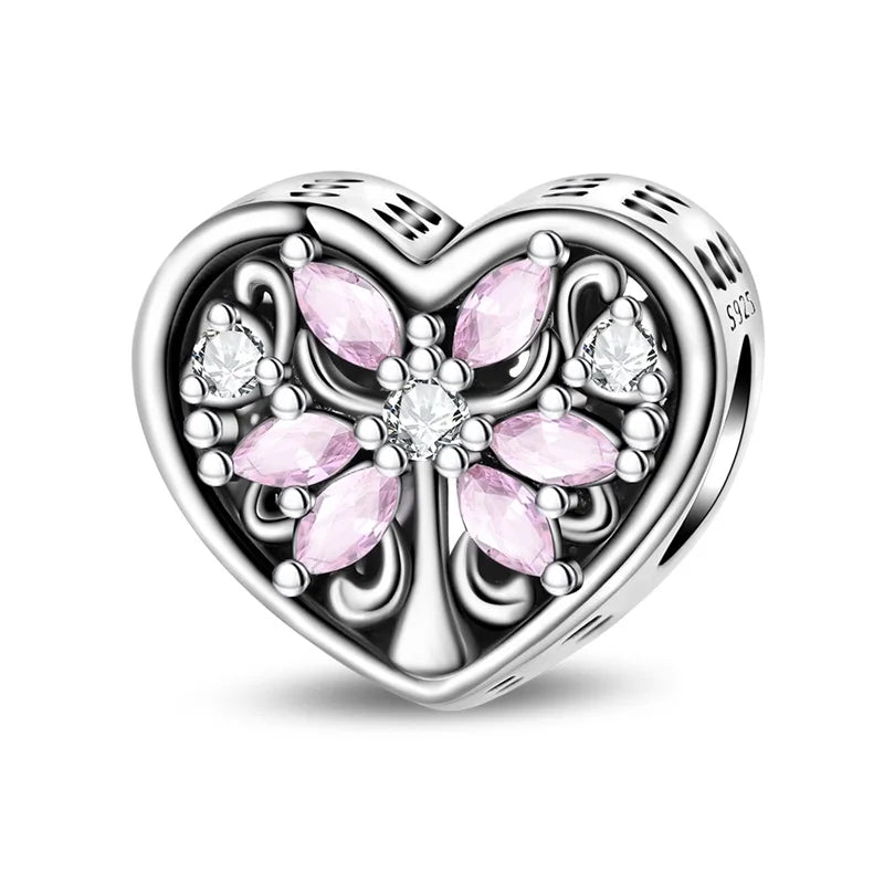 Heart-shaped silver charm with pink gemstones on a white background