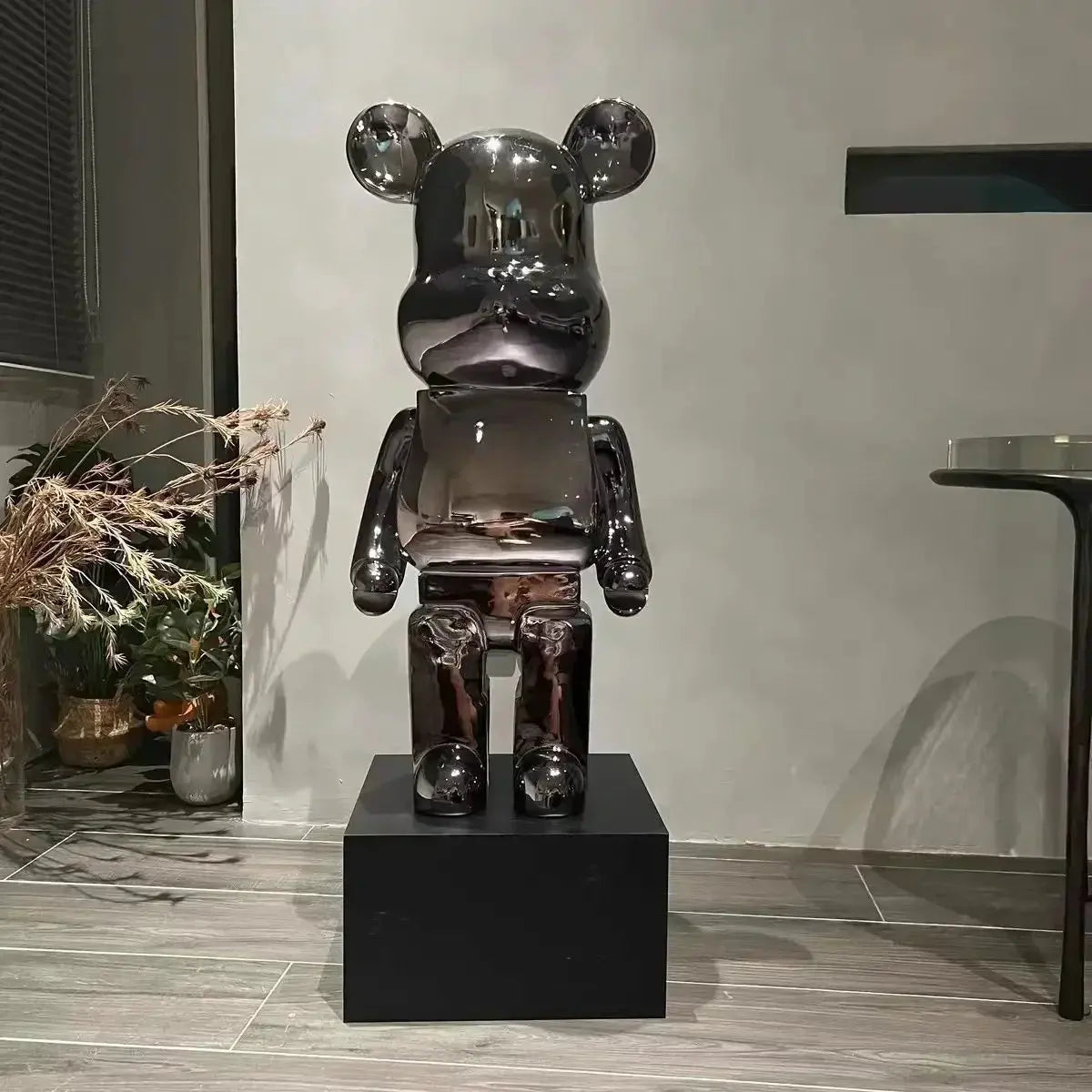 Shiny black bear-like sculpture on a pedestal in an indoor setting bearbrick collectable
