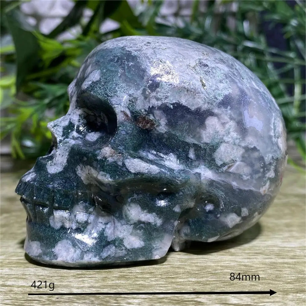 Marble-like stone skull on a wooden surface with greenery in the background