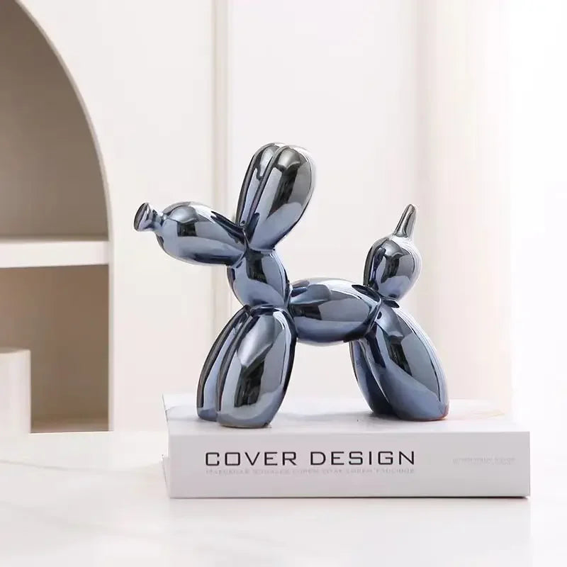 Blue ceramic balloon dog sculpture on a book with a white background