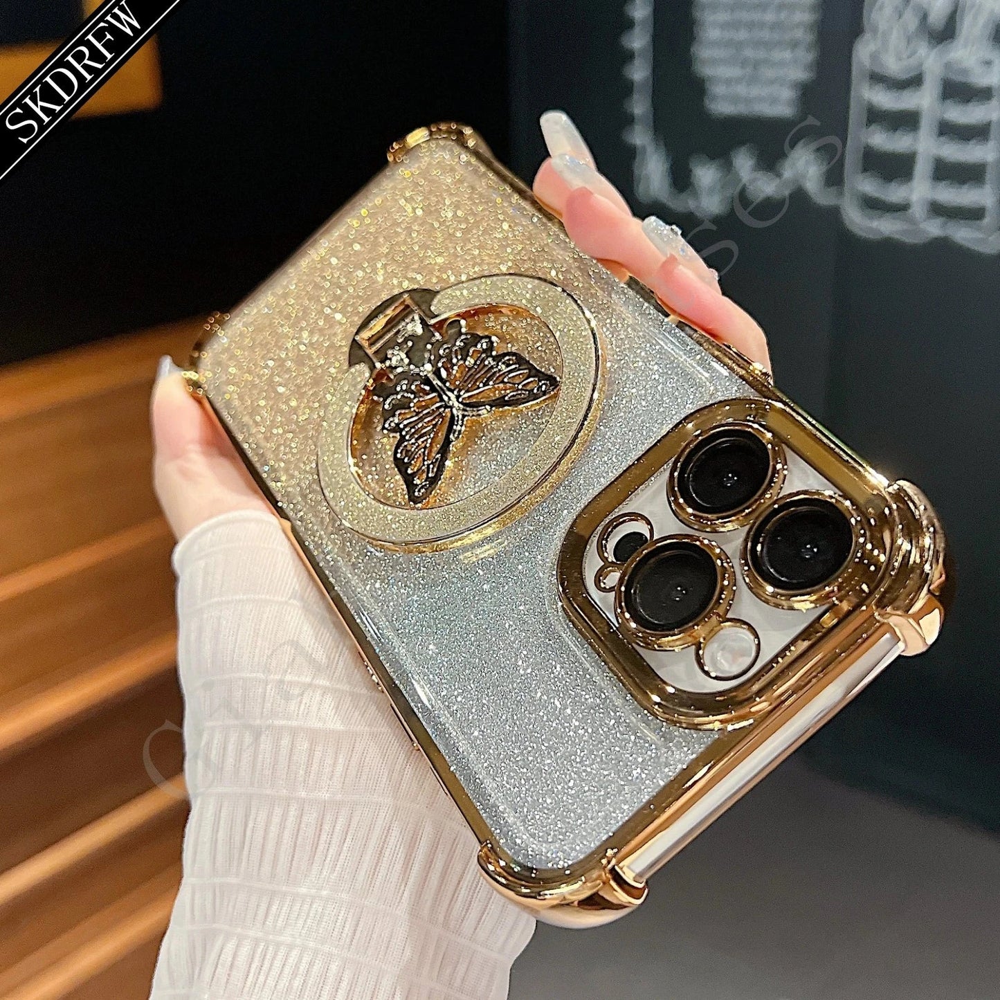 Gold and silver phone case with butterfly design held by a hand