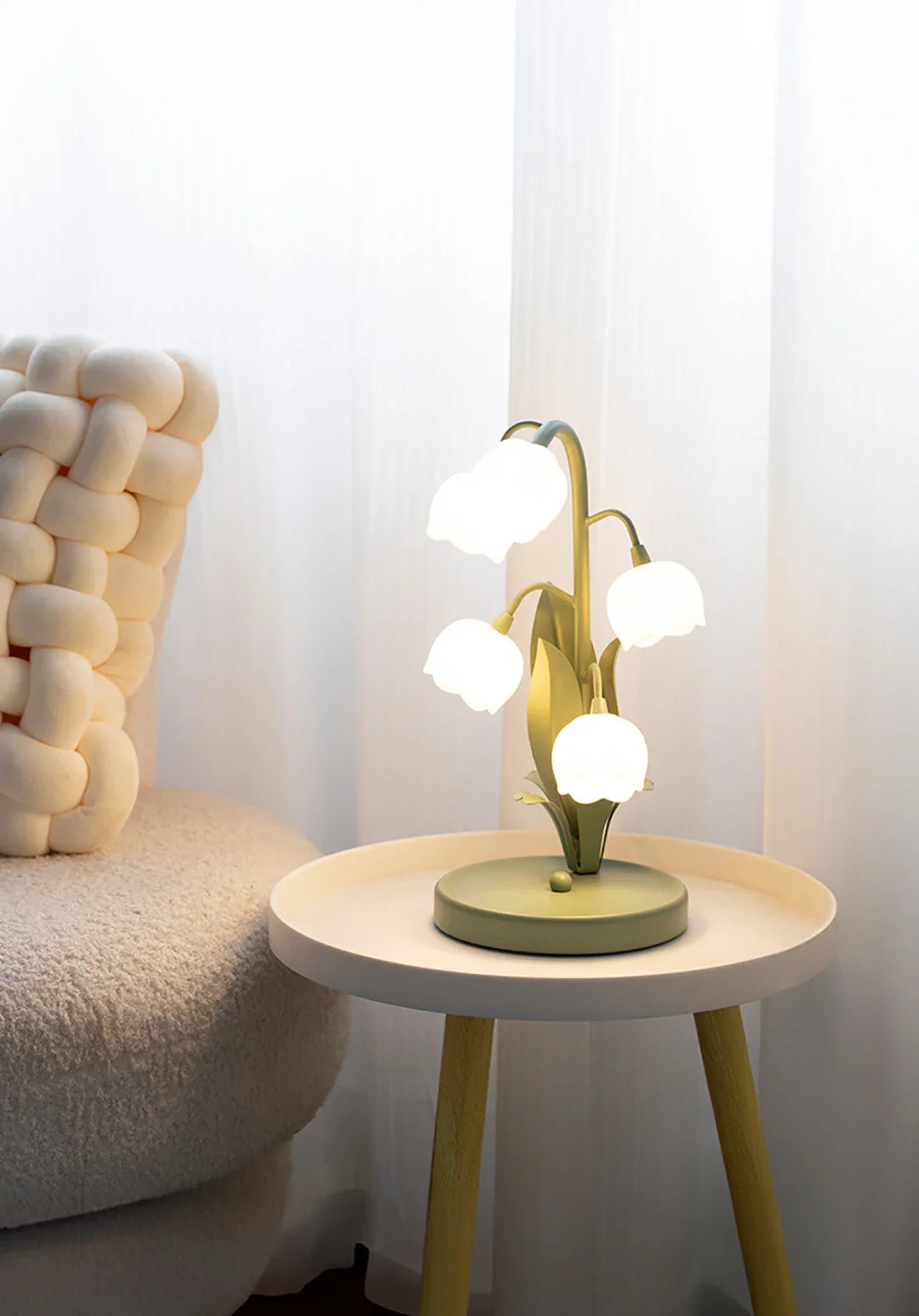 Modern table lamp on a small round table next to a textured chair against a white wall.