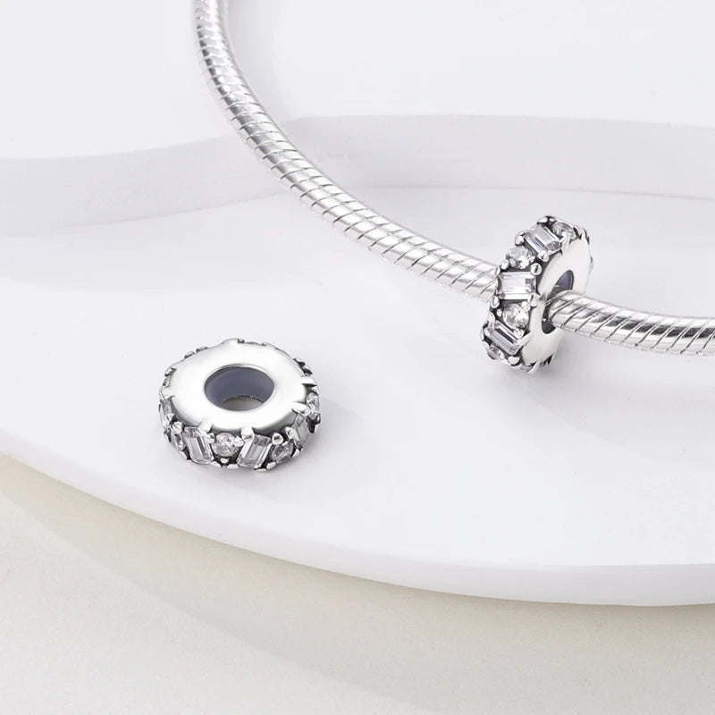 Silver bracelet with two round silver charms on a white surface
