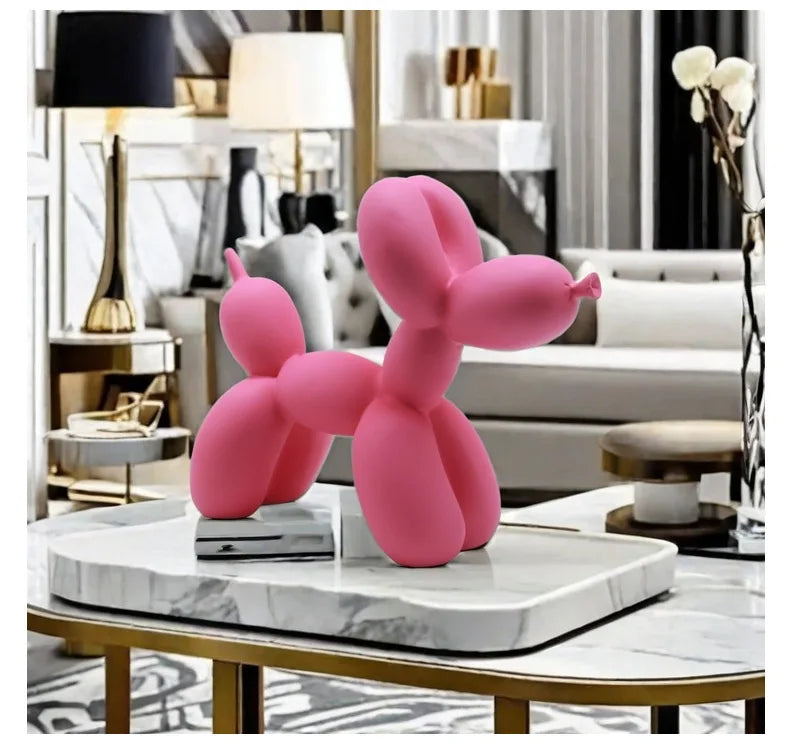 Pink balloon dog sculpture on a marble table in an elegant room.