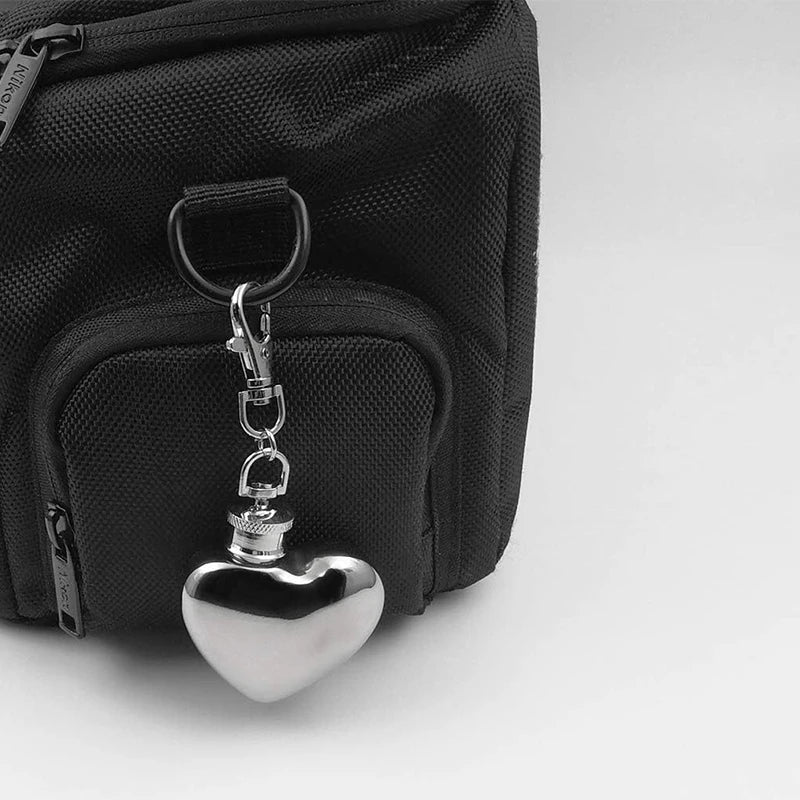 Black bag with a silver heart-shaped keychain on a light gray background