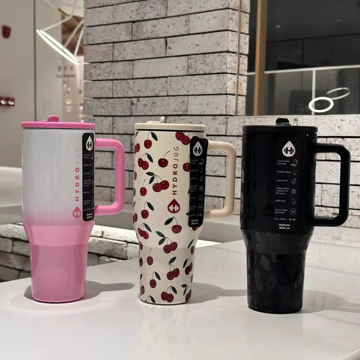 HydroJug Gobelet 40OZ Voyageur Thermos in pink, cherry print, and black variants, highlighting stylish and functional drinkware options.