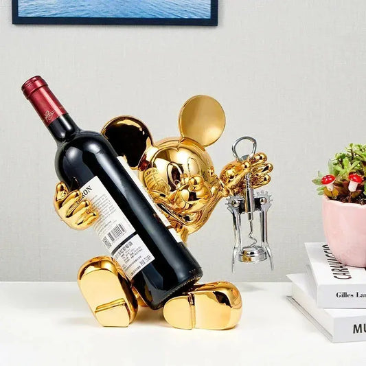 Red wine bottle on a gold wine holder with a decorative heart-shaped object in the background.