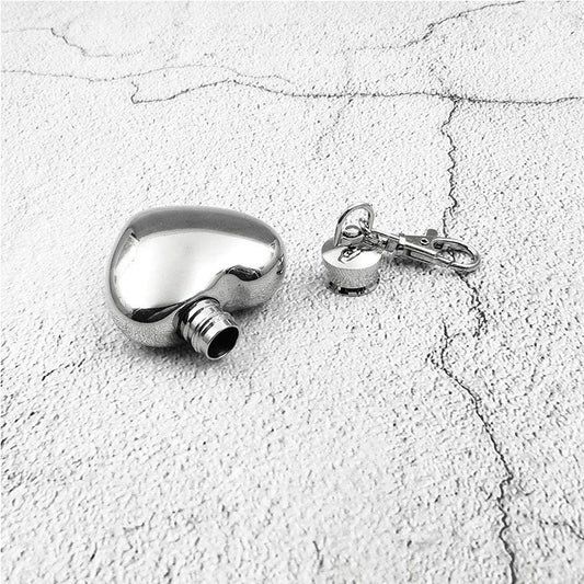 Silver flask and keychain on a textured white surface