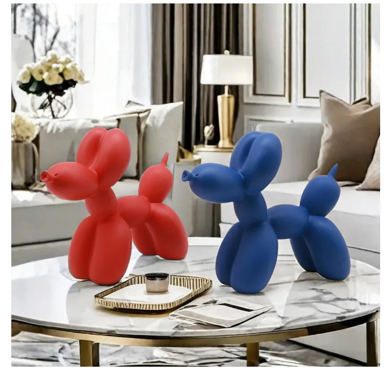 Red and blue balloon dog sculptures on a marble coffee table in a living room.