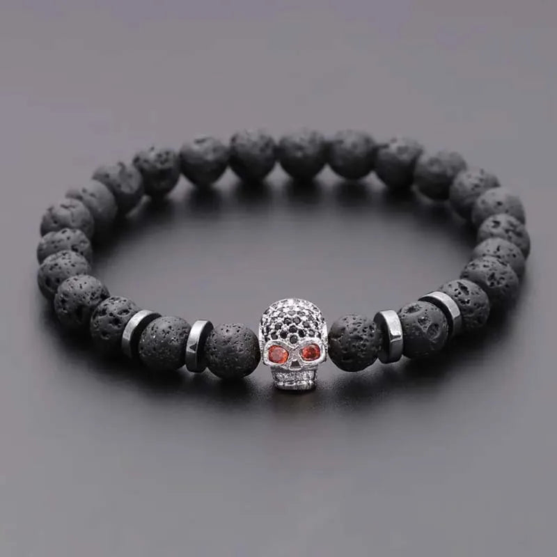 Black beaded bracelet with a skull charm on a gray background