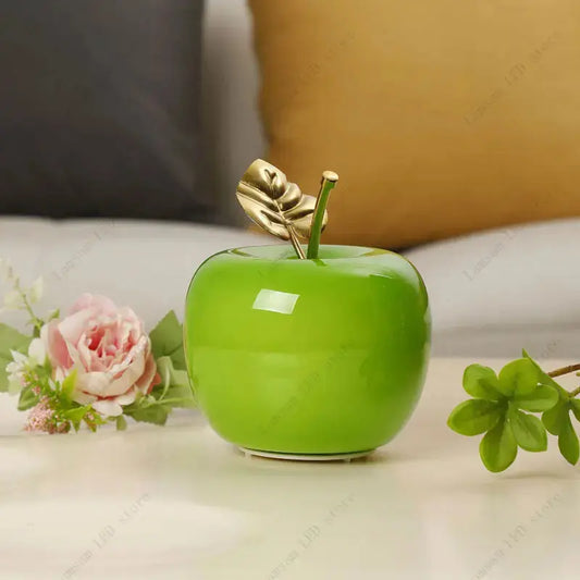 Decorative green apple with a gold leaf on a surface with flowers and leaves.