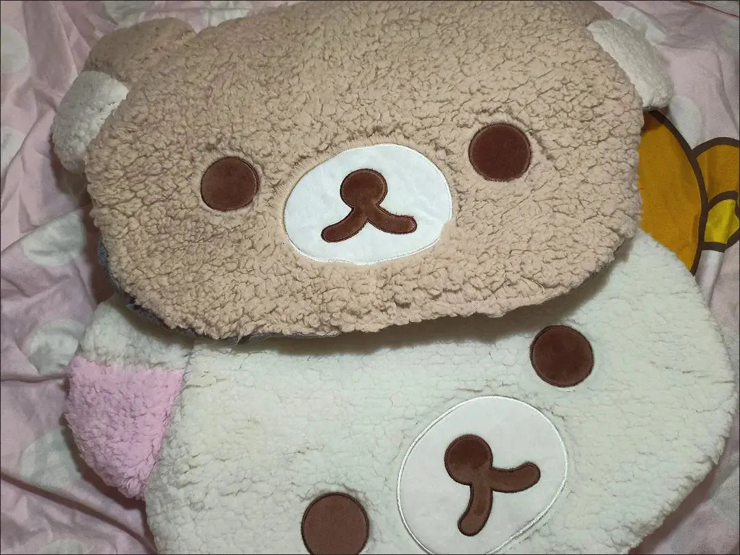Plush toy resembling a bear with a round face and brown eyes on a pink background