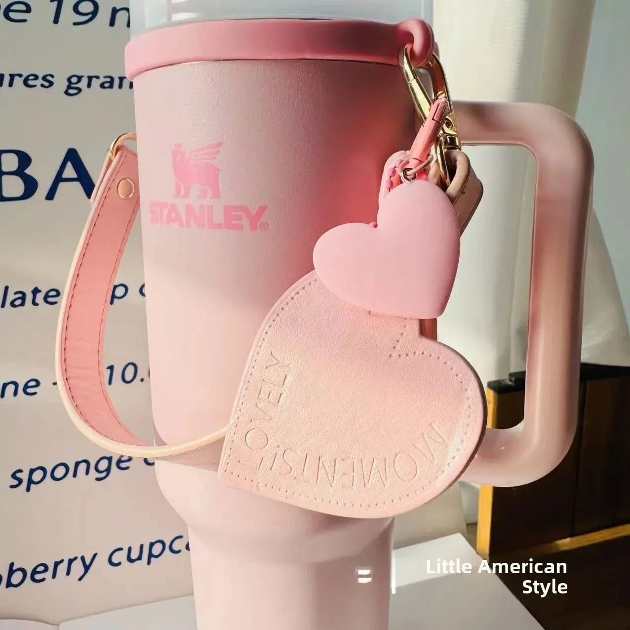 Pink Stanley mug with heart-shaped keychain on a blurred background