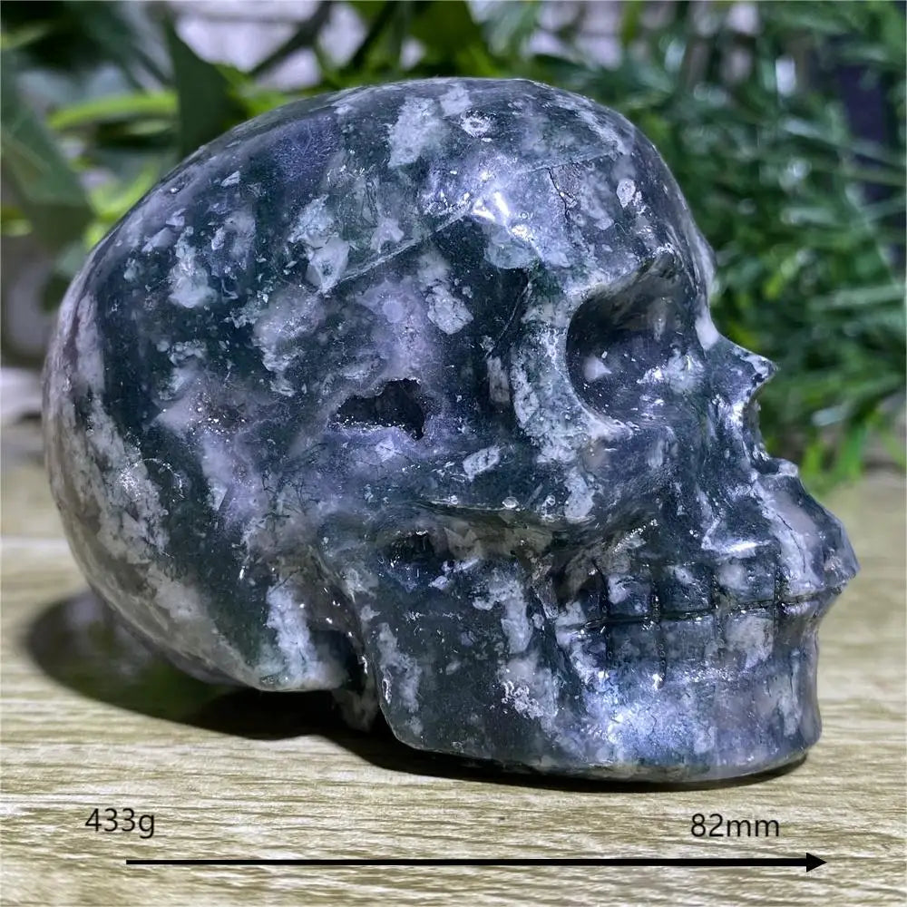 Carved stone skull on a wooden surface with grass in the background