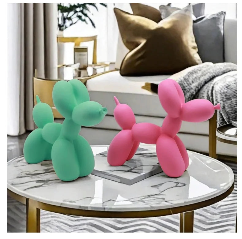 Two balloon dog sculptures, one green and one pink, on a marble coffee table in a living room.