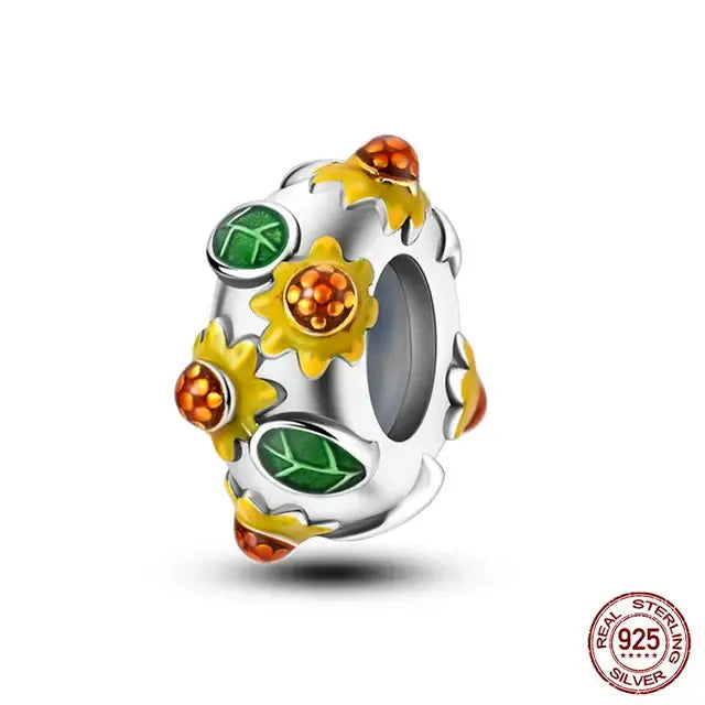 A sterling silver charm featuring a golden sunflower with green leaves on a heart-shaped base.