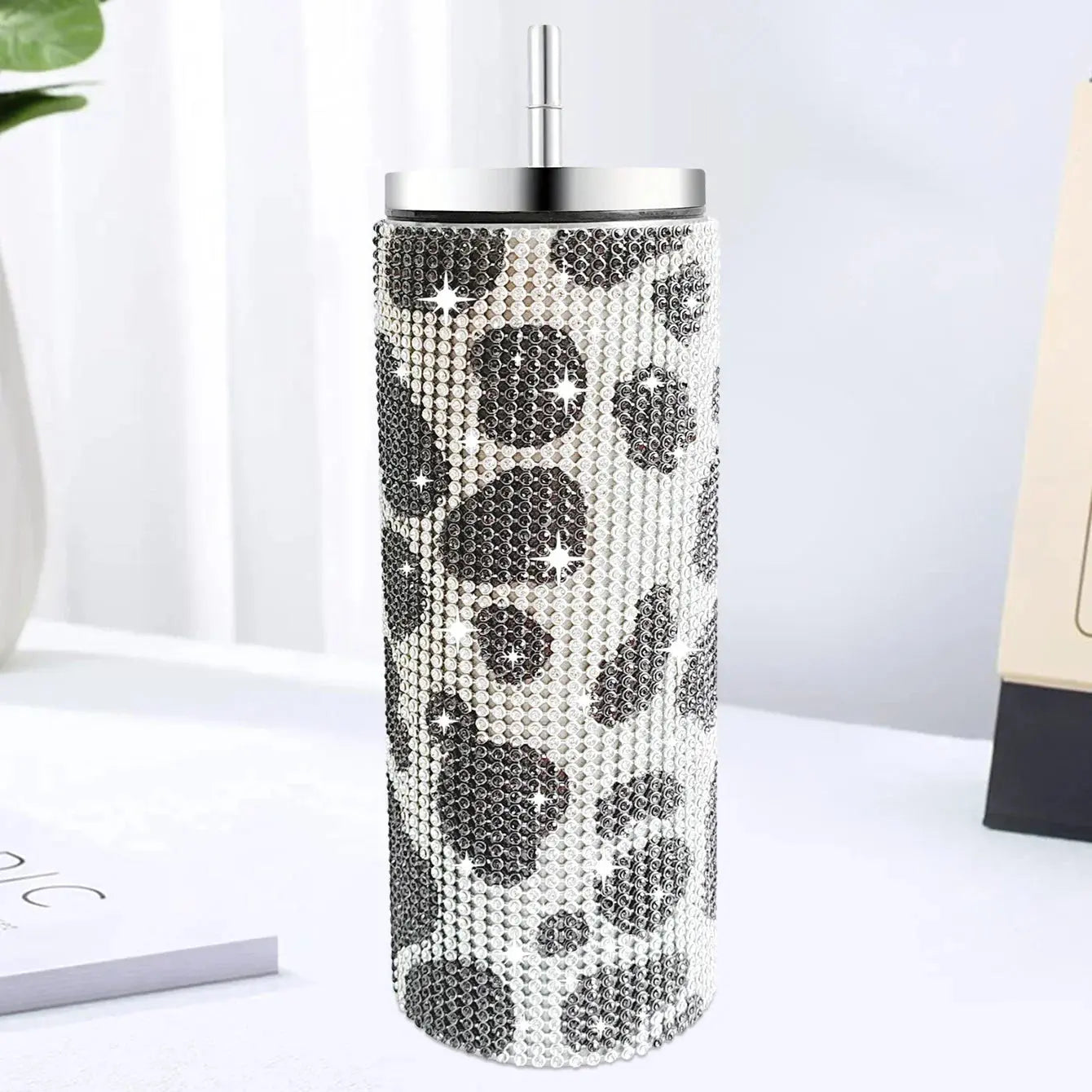Tumbler with black leopard print and clear gemstones on a white surface
