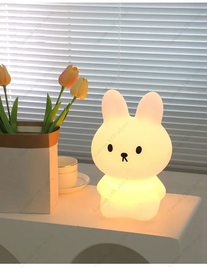 Cute rabbit-shaped night light on a table with tulips in the background