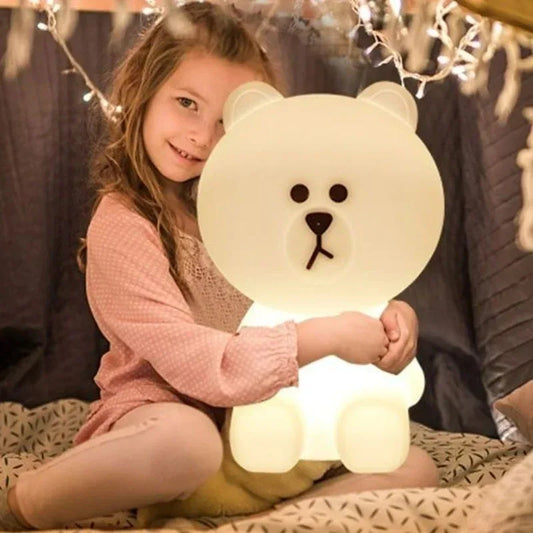 Child holding a glowing bear-shaped lamp in a cozy indoor setting