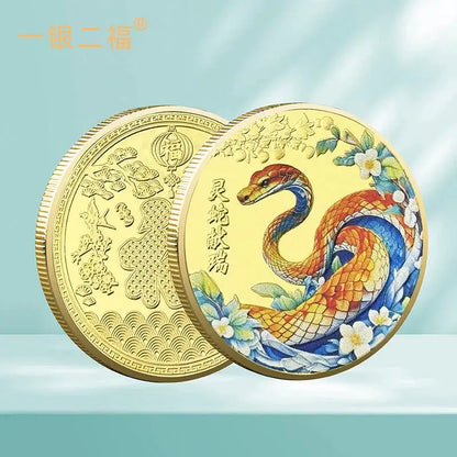 A collectible coin with a 3D relief design of a snake and floral patterns, predominantly in gold and silver colors.
