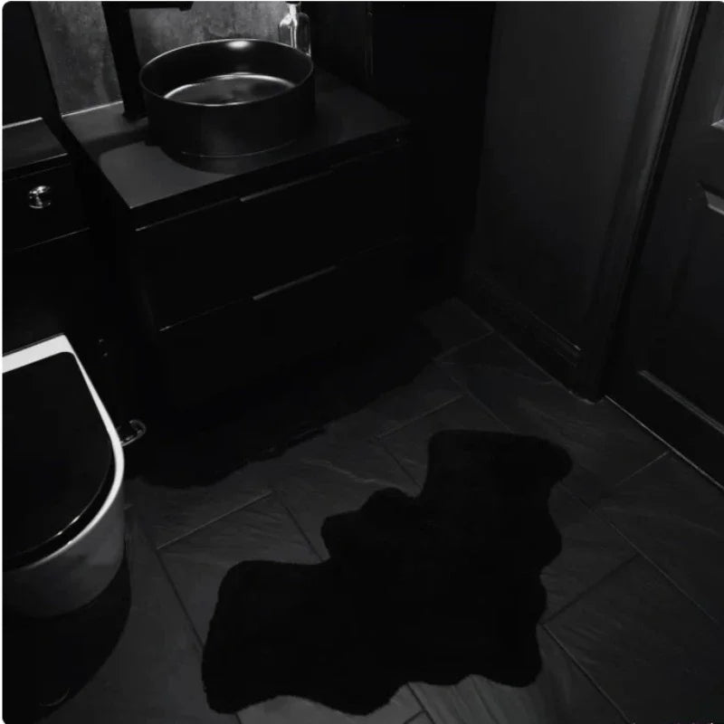Dark bathroom with a sink and toilet, featuring a large black shadow on the floor.