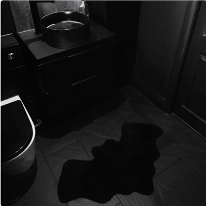 Dark bathroom with a sink and toilet, featuring a large black shadow on the floor.
