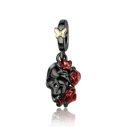 Pendant with black skull design, red roses, and gold butterfly on a white background. pandora style charm pendant. gothic, halloween