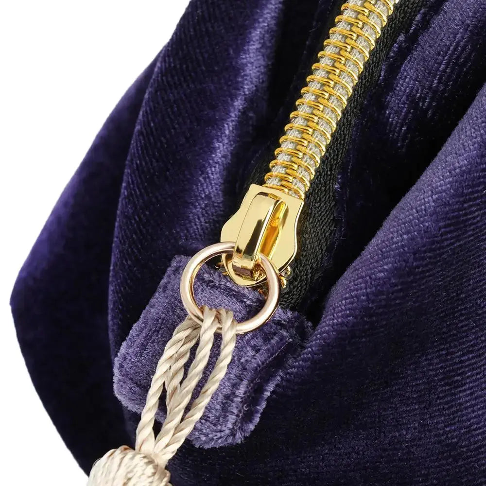 Close-up of a gold zipper on a purple velvet bag with a tassel.