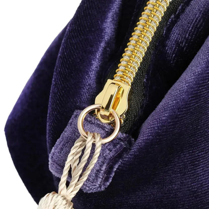Close-up of a gold zipper on a purple velvet bag with a tassel.