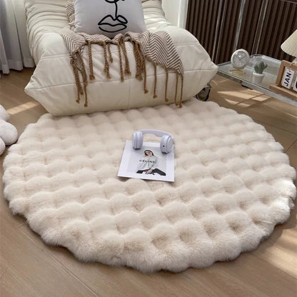 Round white fluffy rug on a wooden floor with a chair and decorative items in the background.