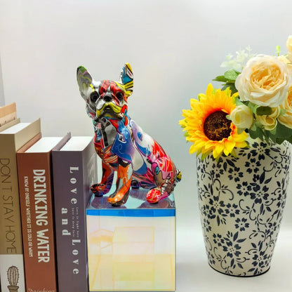 Colorful dog figurine on books with a vase of flowers next to it frenchie french bulldog