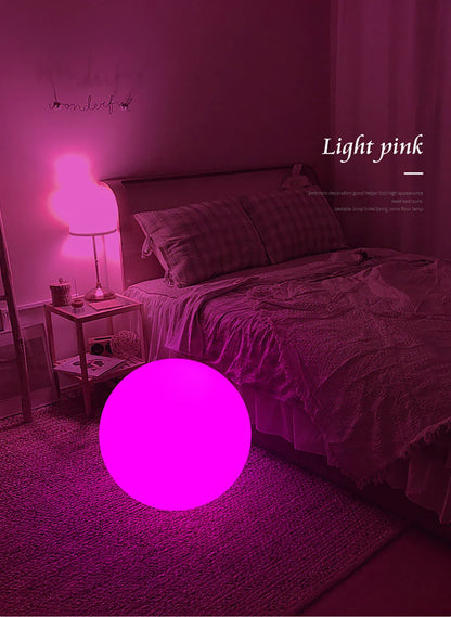 Bedroom with a glowing pink light on the floor, matching the color of the bedding and walls.