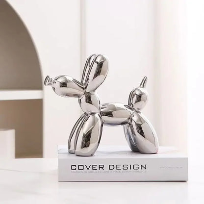 Silver balloon dog sculpture on a white surface with a neutral background