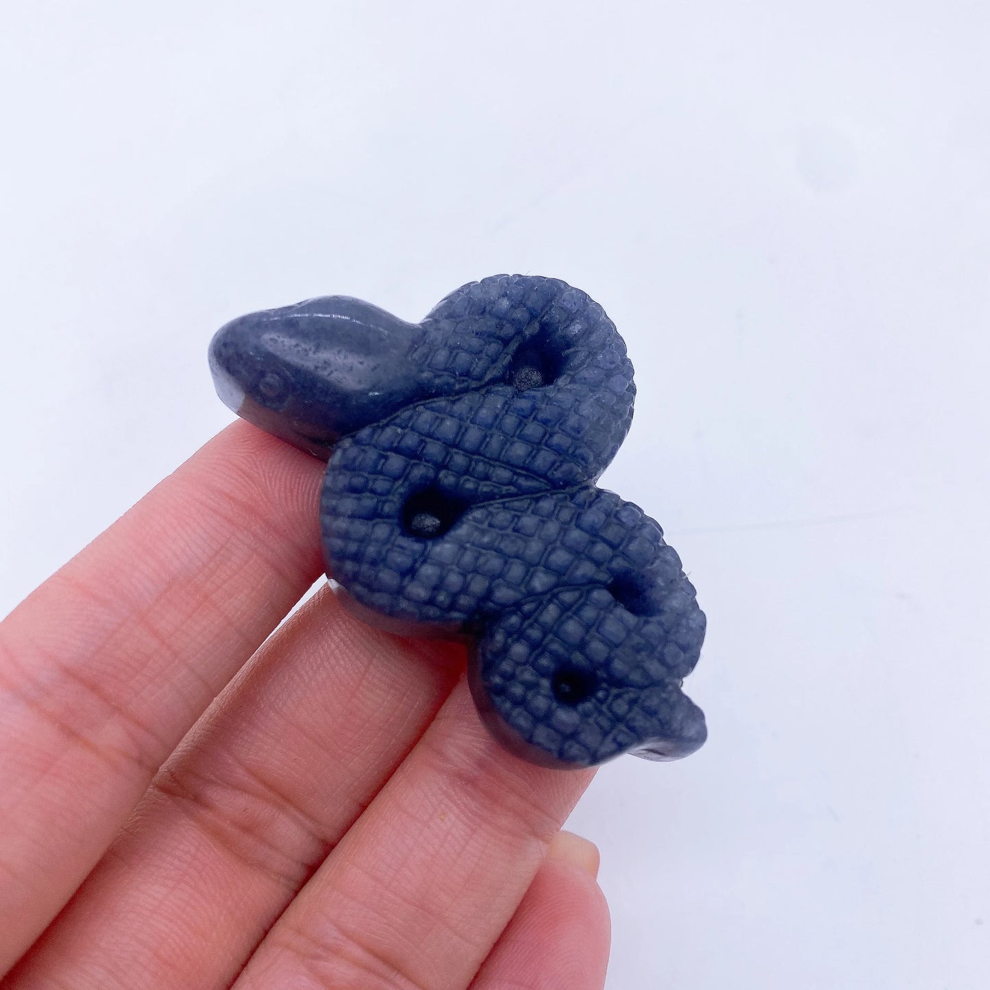 A collage of various crystal snake statues in different colors held in a person's hand.