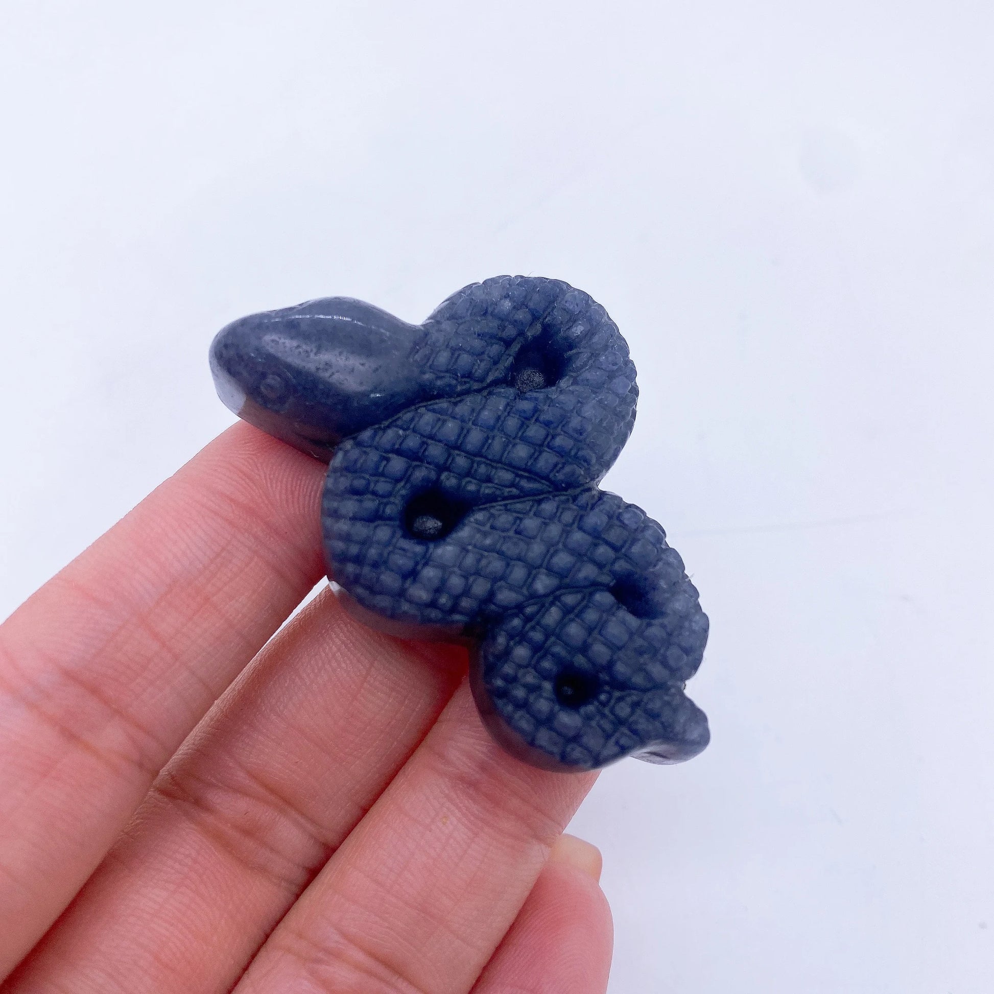 A collage of various crystal snake statues in different colors held in a person's hand.