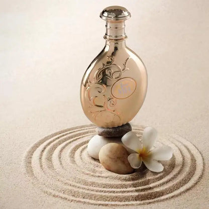 Decorative bottle with floral design on a sand and stone arrangement