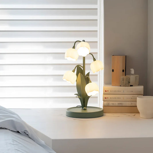 Decorative table lamp with multiple lights on a nightstand next to books and a small plant.