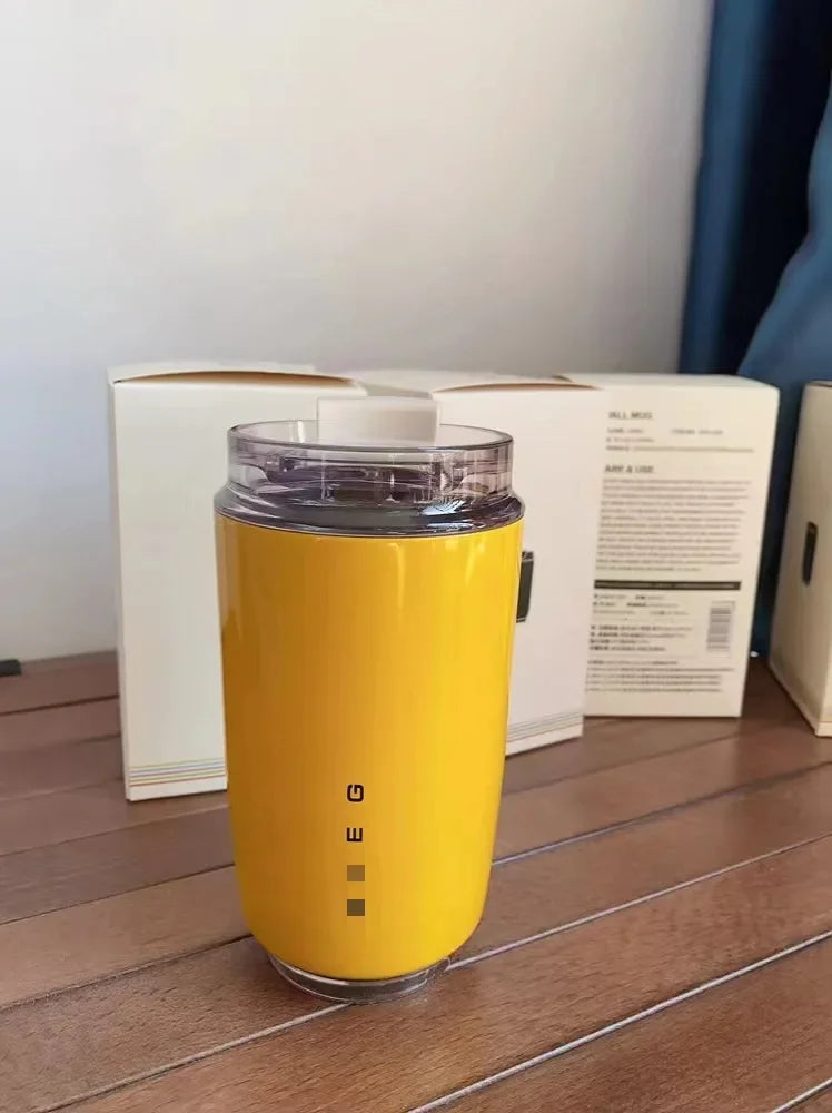 SMEG Yellow mug with a clear lid on a wooden surface, with a white box in the background.