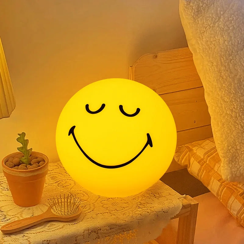 Smiley face lamp on a table with a plant and hairbrush in a cozy room.