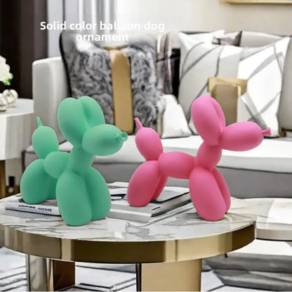 Two balloon dog ornaments, one green and one pink, on a marble table in a living room setting.