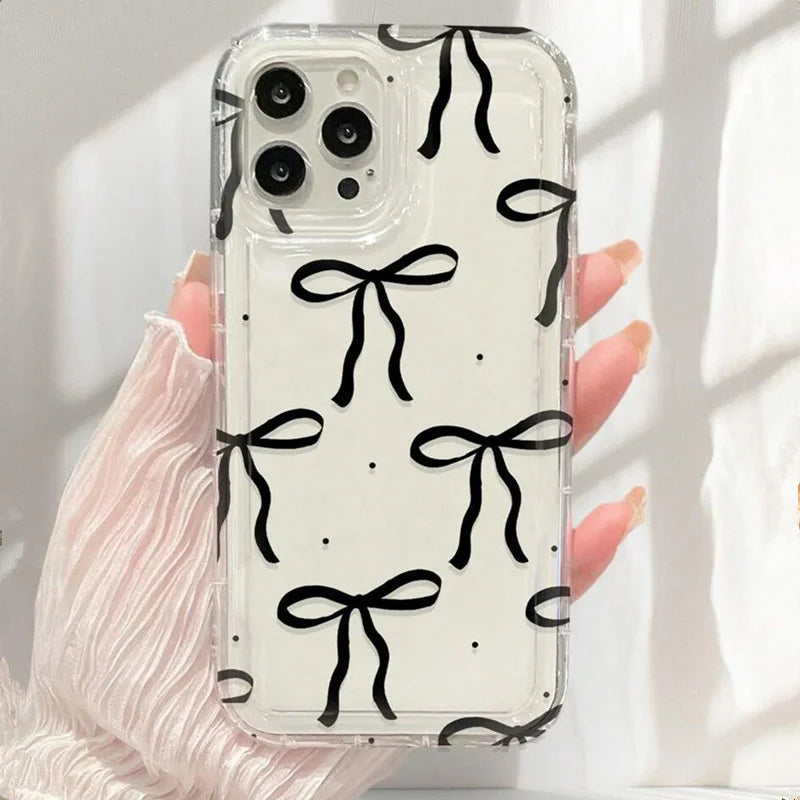 Phone case with black bow pattern held by a hand against a light background