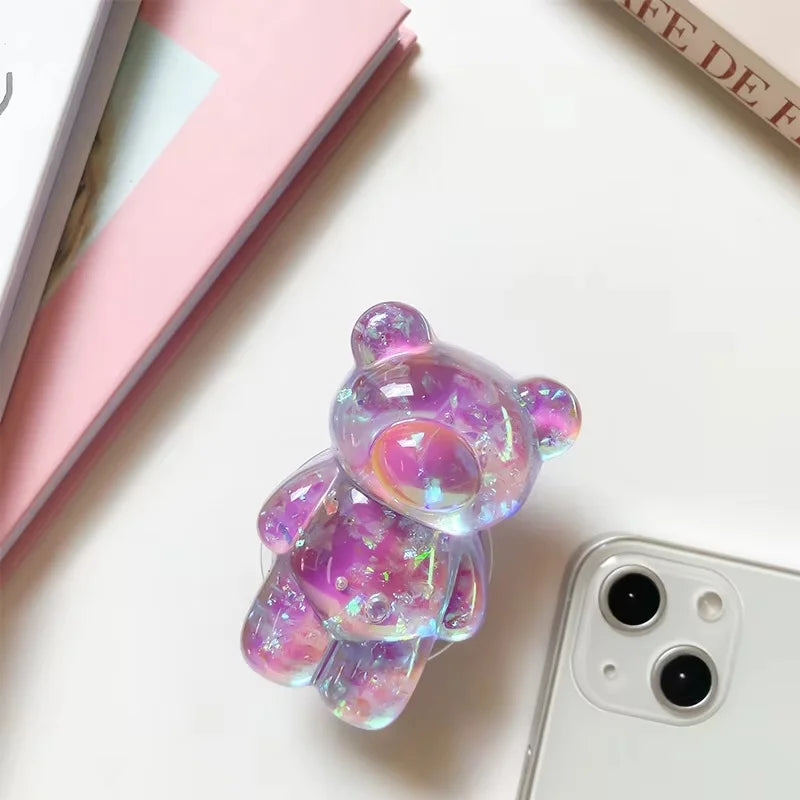 Iridescent bear-shaped phone case next to a smartphone on a light surface
