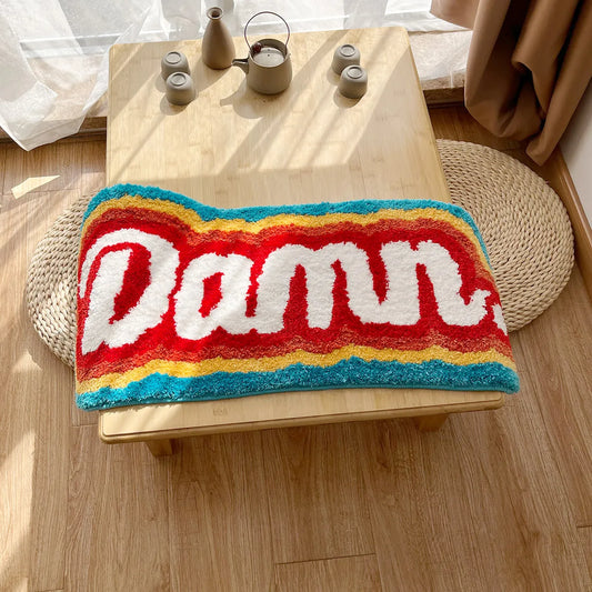 Colorful rug with 'Damn' text on a wooden table