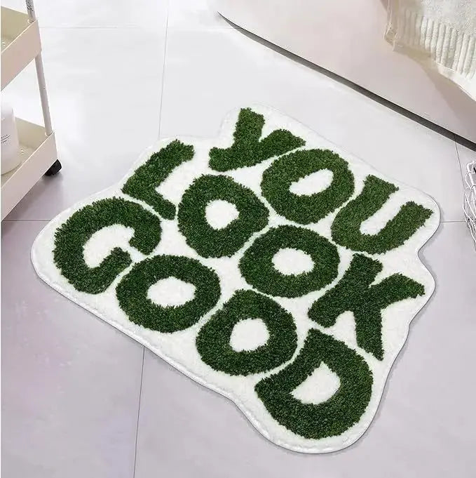 Green and white rug with 'YOU LOOK GOOD' text on a tiled floor. bath mat